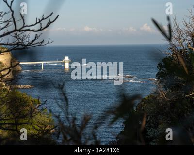 Ein Leuchtturm, der an einer felsigen Küste steht und ein Leuchtfeuer für Schiffe auf dem offenen Meer bietet. Stockfoto