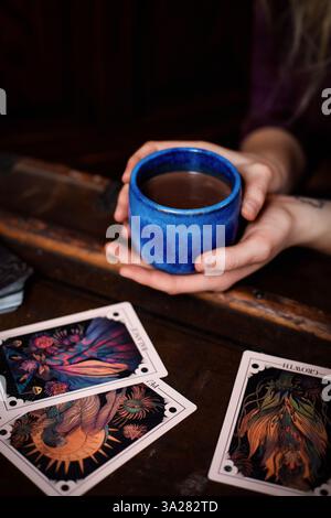 Frau hält zeremoniellen Kakaobecher während spirituellem Kakaoritual mit orakelkarten Stockfoto