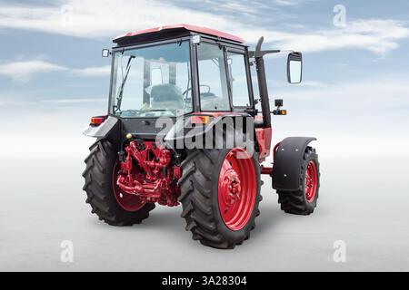 Roter moderner Radtraktor isoliert auf hellem Hintergrund mit Himmel Stockfoto