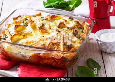 Traditionelle bulgarische oder Balkantorte Banitsa aus Filo-Teig, Frischkäse und Spinat, serviert mit Sahne und Kaffee auf hölzernem Hintergrund. Rustikal Stockfoto