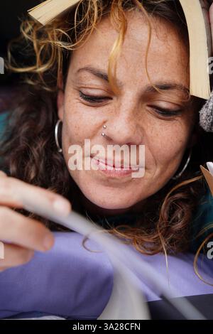 Nahporträt einer Reifen Frau mit einem Buch, ihr Gesicht versteckt unter dem Buch. Weltbuchtag Stockfoto