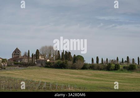 Friedliche Landschaft mit der Kirche Haux in Gironde umgeben von üppiger Natur und Zypressen unter klarem Himmel Stockfoto