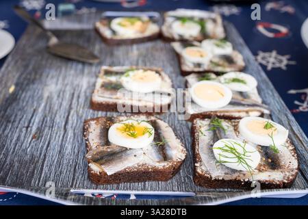 Sandwich mit gewürzter Sprotte: Estnische Sandwich mit würziger gesalzener Sprotte, Butter, gekochtem Ei, frischem Dill auf einer Scheibe nationalem Roggenbrot. Stockfoto