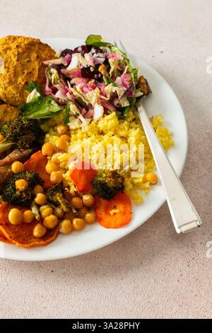 Ein reichhaltiges, ausgewogenes Frühstück mit Linsen- und Zucchini-Pfannkuchen, Hirse, gebackenem Hähnchenhals, gerösteten Süßkartoffeln, Brokkoli, Karotten, Kichererbsen und Stockfoto