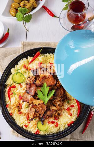 Tajin mit Couscous, Gemüse und Fleisch auf weißem Hintergrund Stockfoto
