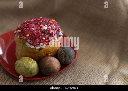 Osterkuchen mit Ostereiern auf rotem Teller auf einem Tisch mit Tischdecke Stockfoto