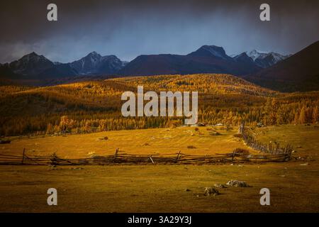 Blick auf die rustikale Landschaft mit farbenfrohem Herbstlaub, Holzzäunen und majestätischer Bergkulisse. Stockfoto