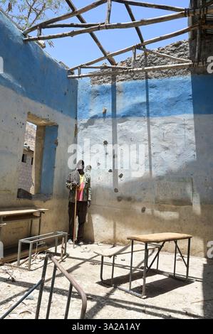 ÄTHIOPIEN, Bezirk Yechila, Dorf SHEWEATE HUGUM, zerstörte Schule während des Tigray-Krieges 2020-2022 zwischen den mit der äthiopischen Bundesregierung und Eritrea verbündeten Kräften und der Tigray Volksbefreiungsfront TPLF, TPLF Fighter / Äthiopien, Tigray, Folgen des Tigray Kriege 2020-2022, Distrikt Yechila, Dorf SHEWEATE HUGUM, zerstörte Schule, Gerse Tadese, Tigrayischer Kämpfer der TPLF, 51 Jahre alt, sein Sohn ist im Krieg gefallen mit 22 Jahren, Gewehr Einschüsse Stockfoto
