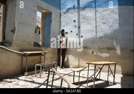 ÄTHIOPIEN, Bezirk Yechila, Dorf SHEWEATE HUGUM, zerstörte Schule während des Tigray-Krieges 2020-2022 zwischen den mit der äthiopischen Bundesregierung und Eritrea verbündeten Kräften und der Tigray Volksbefreiungsfront TPLF, TPLF Fighter / Äthiopien, Tigray, Folgen des Tigray Kriege 2020-2022, Distrikt Yechila, Dorf SHEWEATE HUGUM, zerstörte Schule, Gerse Tadese, Tigrayischer Kämpfer der TPLF, 51 Jahre alt, sein Sohn ist im Krieg gefallen mit 22 Jahren, Gewehr Einschüsse Stockfoto