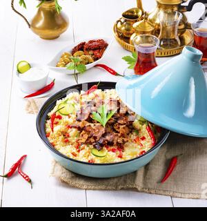 Tajin mit Couscous, Gemüse und Fleisch auf weißem Hintergrund Stockfoto