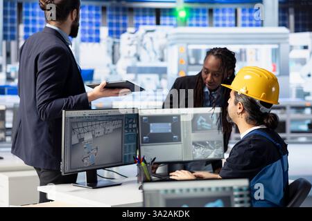 Das Engineering-Team der Photovoltaik-Fabrik führt Brainstorming durch und überprüft Systemprotokolle, um betriebliche Ineffizienzen zu identifizieren. Mitarbeiter von Solarpaneelen, die Fertigungsparameter anpassen Stockfoto