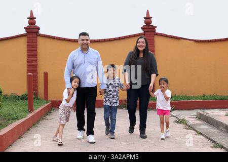 Brünette Latin Familie von Vater, Mutter, Töchtern und Sohn spazieren zusammen im Park Hand in Hand verbringen schöne Zeit Stockfoto