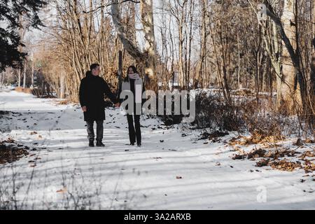 Ein Paar genießt einen Winterspaziergang auf einem verschneiten Pfad an einem sonnigen Tag Stockfoto