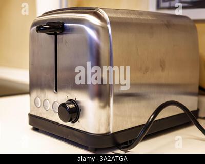 Nahaufnahme eines modernen Toasters aus Edelstahl, der auf einer Küchenarbeitsplatte platziert wird und sein schlankes Design, die Drehregler und die Tasten betont, die typisch für Sie sind Stockfoto