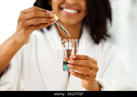 Schönheit Und Hautpflege. Lächelnde Schwarze Frau Holding Flasche Mit Feuchtigkeitsspendende Gesicht Serum Stockfoto