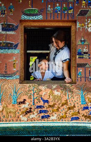 Mutter und Kind im Wat Xieng Thong, Luang Prabang, Laos. Traditionelle Kunst, Kulturfenster Stockfoto