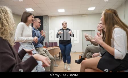 Junge Menschen kommunizieren in Gebärdensprache in einem Universitätsklassenzimmer. Stockfoto