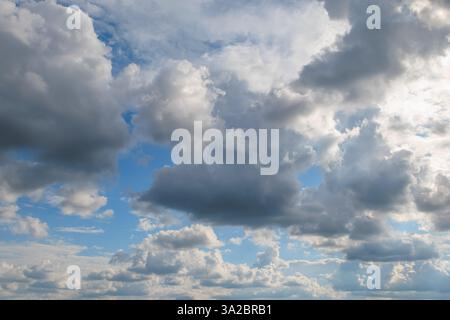 Ein landschaftlich schöner Himmel mit einer Mischung aus dunklen und flauschigen Wolken, die eine dramatische und dynamische Atmosphäre mit blauen Flecken schaffen. Stockfoto