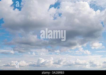 Ein landschaftlich schöner Himmel mit einer Mischung aus dunklen und flauschigen Wolken, die eine dramatische und dynamische Atmosphäre mit blauen Flecken schaffen. Stockfoto