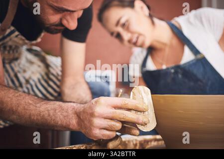 Hand-, Keramik- und Bildhauer-Werkzeug mit Personen im Studio für Startup aus Keramik, Ton oder Steingut. Kunst, Kreativität oder Teamwork mit Mann und Frau in Stockfoto