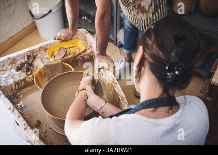 Menschen, Team und Töpferkunst im Atelier, arbeiten zusammen und schnitzen Ton für keramisches Kunsthandwerk. Unterricht, Ausrüstung und Hilfestellung beim Unterricht in der Werkstatt Stockfoto