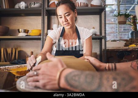 Menschen, Team und Töpferei im Studio, arbeiten zusammen und schnitzen Ton für keramische Handwerke. Unterricht, Ausrüstung und Hilfe beim Unterricht an Stockfoto