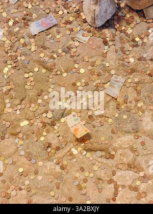 Ein Stapel Münzen und Scheine auf dem Boden. Die Münzen sind über den Boden verstreut, und die Scheine stapeln sich in der Mitte. Die Szene gibt einen ab Stockfoto