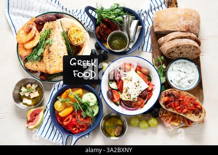 Griechische Küche Hintergrund. FSH, Pita, griechischer Salat, Tzatziki, Feta, Oliven. Traditionelle griechische Gerichte auf hellem Hintergrund. Draufsicht. Stockfoto