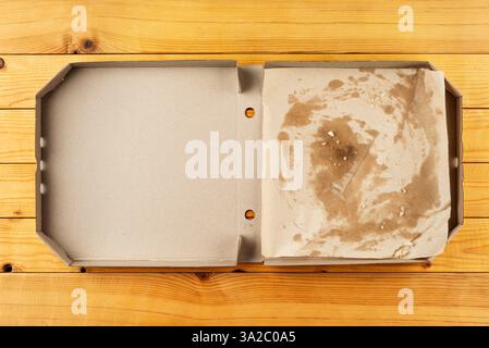 Leere Pizzaschachtel mit Brotkrumen auf natürlichem Holztisch mit flachem Blick Stockfoto