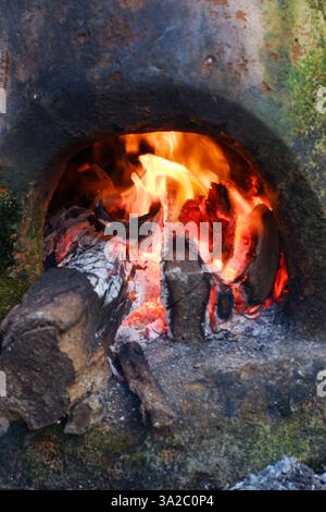 NAHKAMIN, Brennholz in einem traditionellen Steinofen, offener Backofen zum Kochen von Fleisch, Fisch und anderen Speisen mit einem traditionellen Ofen. Stockfoto