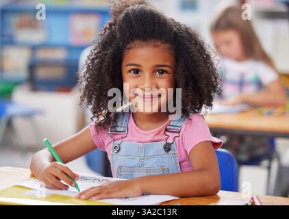 Schule, Kind und Porträt mit Färbung im Klassenzimmer für kreative Tests, Lernentwicklung oder Kunstaktivitäten. Kindergarten, Mädchen Studentin oder glücklich Stockfoto