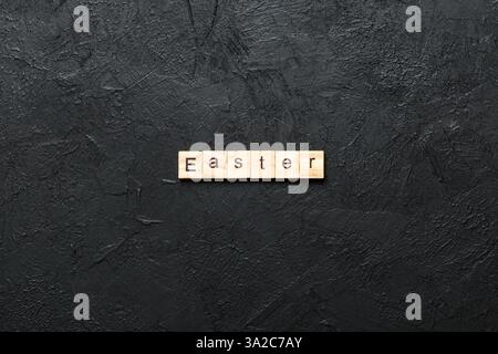 Osterwort auf Holzblock geschrieben. Ostertext auf Zementtisch für Ihren Entwurf, Konzept. Stockfoto