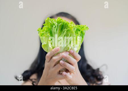 Schwarze Frau, die einen Kopf grünen Salat über ihr Gesicht hält. Frau mit Gewichtsdiät-Lifestyle-Konzept. Selektiver Fokus. Stockfoto