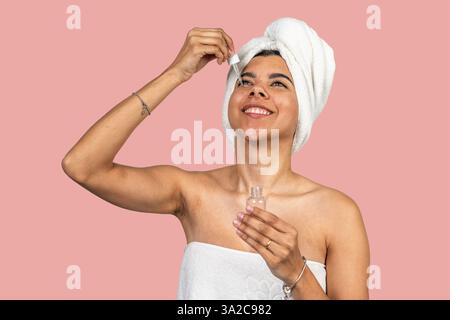Schönheitsbehandlung mit Naturkosmetik. Frau, die Augenkonturserum mit einem Tropfer aufträgt und eine Flasche hält Stockfoto