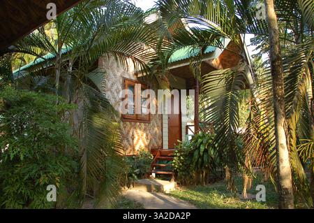 Charmanter Bambusbungalow mit grünem Dach, eingebettet zwischen tropischen Palmen und üppigem Grün in Ao Nang, Thailand, bietet eine friedliche und rustikale Atmosphäre Stockfoto