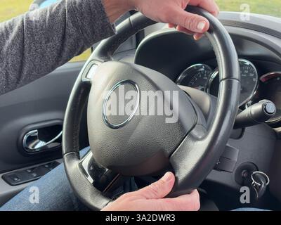 Nahaufnahme kräftiger männlicher Hände, die ein Autolenkrad fest halten, symbolisieren Kontrolle, Selbstvertrauen und Fokus auf das Fahren. Starke Männliche Hände, Die Das Lenkrad Des Fahrzeugs Greifen. Hochwertige Fotos Stockfoto