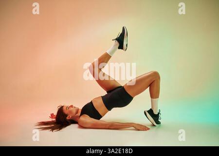 Seitenansicht, Übung ausführen. Eine junge Frau in Fitnesskleidung ist im Studio. Stockfoto
