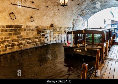 Hölzerne Vodouch-Boote liegen am Abfahrtspier in der Nähe der Karlsbrücke, bereit für eine Besichtigungstour entlang der Moldau im Stadtzentrum von Prag, Tschechien Stockfoto