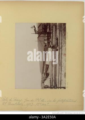 Das Foto von Eugène Atget aus dem Jahr 1913 zeigt den Bahnhof Gare du P.L.M. (Paris-Lyon-Méditerranée) in der Nähe der Porte de Bercy, der sich auf den Befestigungsanlagen am Boulevard Poniatowski befindet. Das Bild dokumentiert die Integration der Verkehrsinfrastruktur in die historischen Verteidigungsbauten von Paris im frühen 20. Jahrhundert. Stockfoto