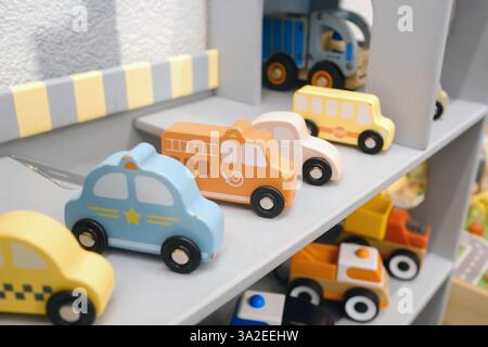 Auf einem stabilen grauen Regal in einem fröhlichen Spielzimmer finden sich farbenfrohe Spielzeugautos und Trucks aus Holz, die Kinder zum kreativen und kreativen Einsatz einladen Stockfoto