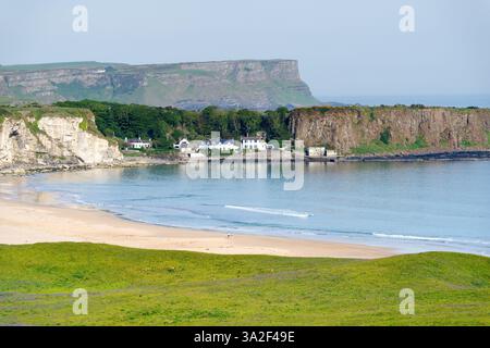 White Park Bay an der nördlichen Küste von Antrim, Nordirland. Die Basaltklippen des Giants Causeway erheben sich hinter dem Fischerdorf Portbradden Stockfoto
