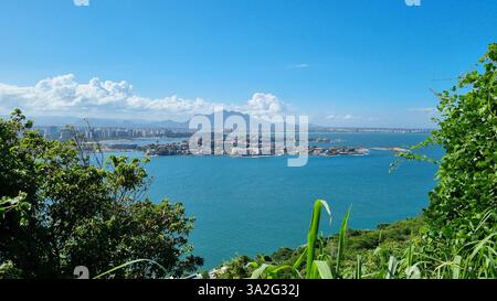 Pulsierendes blaues Wasser erstreckt sich über den Rahmen und umgibt eine Insel mit eleganten Häusern und üppigem Grün. Stockfoto