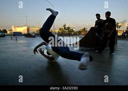 Im Skatepark gegenüber von der Bowlingbahn Eric Costilla 15 macht ein paar Break Dancing, während Freunde zusehen. Der Skatepark befindet sich an der gleichen Stelle wie das neue Theater in der Stadt. Wie so viele Städte im zentralen Tal hat auch die Innenstadt von Dinuba in den letzten Jahren zu kämpfen. Aber eine Sanierung hat stattgefunden, und es begann mit dem Kauf einer Bowlingbahn. Nach drei Jahren Stadtbetrieb kaufte ein privater Betreiber die Gasse im März, wobei auch andere neue Unternehmen einzogen. Gegenüber der Bowlingbahn wurde auch ein neues Theater gebaut. Foto am Mittwoch, 16. Juni 2004. (C Stockfoto
