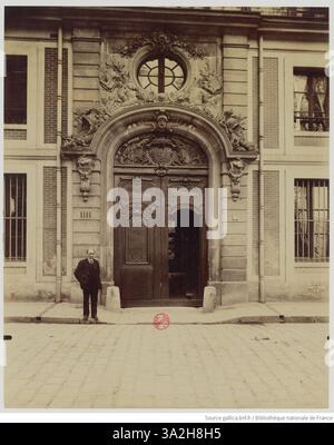 Dieses Foto von Eugène Atget zeigt die Porte 6 (Tor 6) auf der Avenue de Paris im Schloss von Versailles. Das Bild zeigt die architektonischen Details und das große Design des Eingangs, eingerahmt von den umliegenden Gärten. Stockfoto
