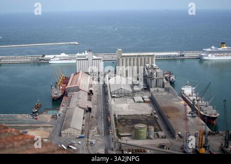 Aktiver Hafen mit Frachtschiffen, Silos und einem Kreuzfahrtschiff. Luftaufnahme, industrielle Infrastruktur und trübe Atmosphäre Stockfoto