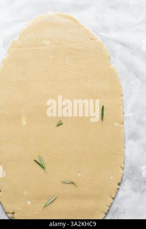 Draufsicht auf ausgerollten Rosmarinzucker-Keksenteig, Prozess der Herstellung von ausgeschnittenen Zuckerkeksen Stockfoto