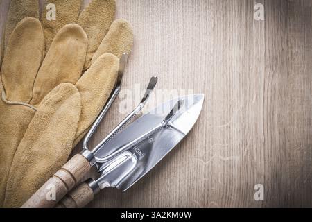 Gartenkelle aus Stahl mit Schaufel und Lederschutzhandschuhen auf Holzbrett Landwirtschaftskonzept Stockfoto