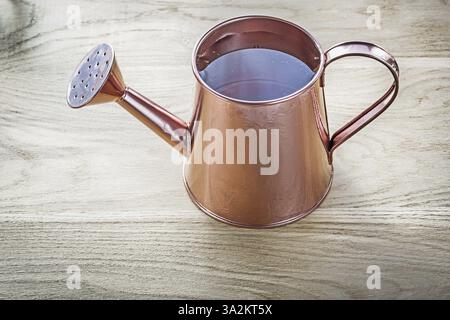 Vintage-Bewässerungstopf mit Wasser auf Holzbrett Landwirtschaftskonzept Stockfoto