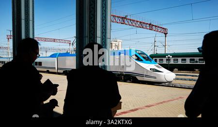 Afrosiyab Hochgeschwindigkeits-Hochgeschwindigkeitszug von Usbekistan, der am Bahnsteig am Bahnhof Buchara Vokzal steht und Passagier in Silhouette in Usbekistan ist Stockfoto
