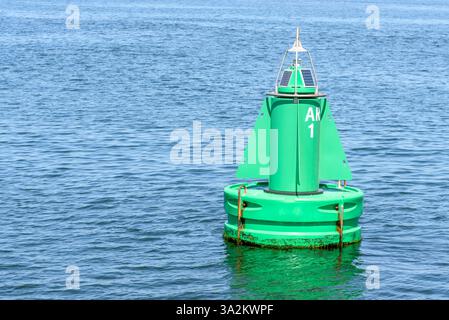 Nahaufnahme einer grünen Sonnenboje, die einen Schifffahrtskanal in einem Hafen markiert Stockfoto